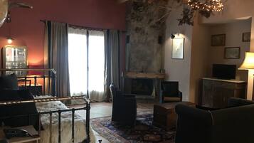 A cozy living room with a fireplace, a sofa, a coffee table, and a television.