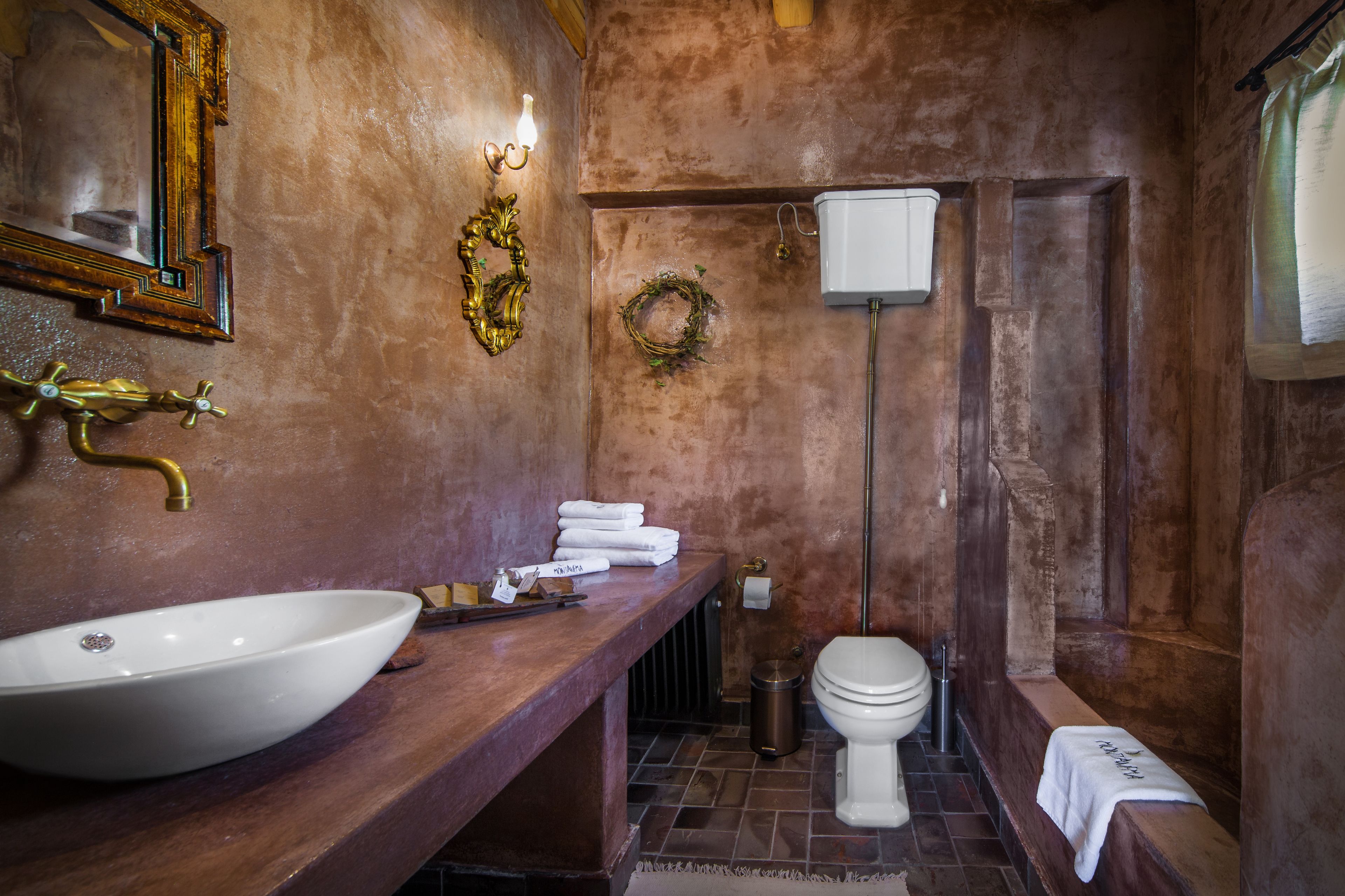 Une salle de bain avec un grand lavabo blanc, un meuble-lavabo en bois, des toilettes blanches et un porte-serviettes.