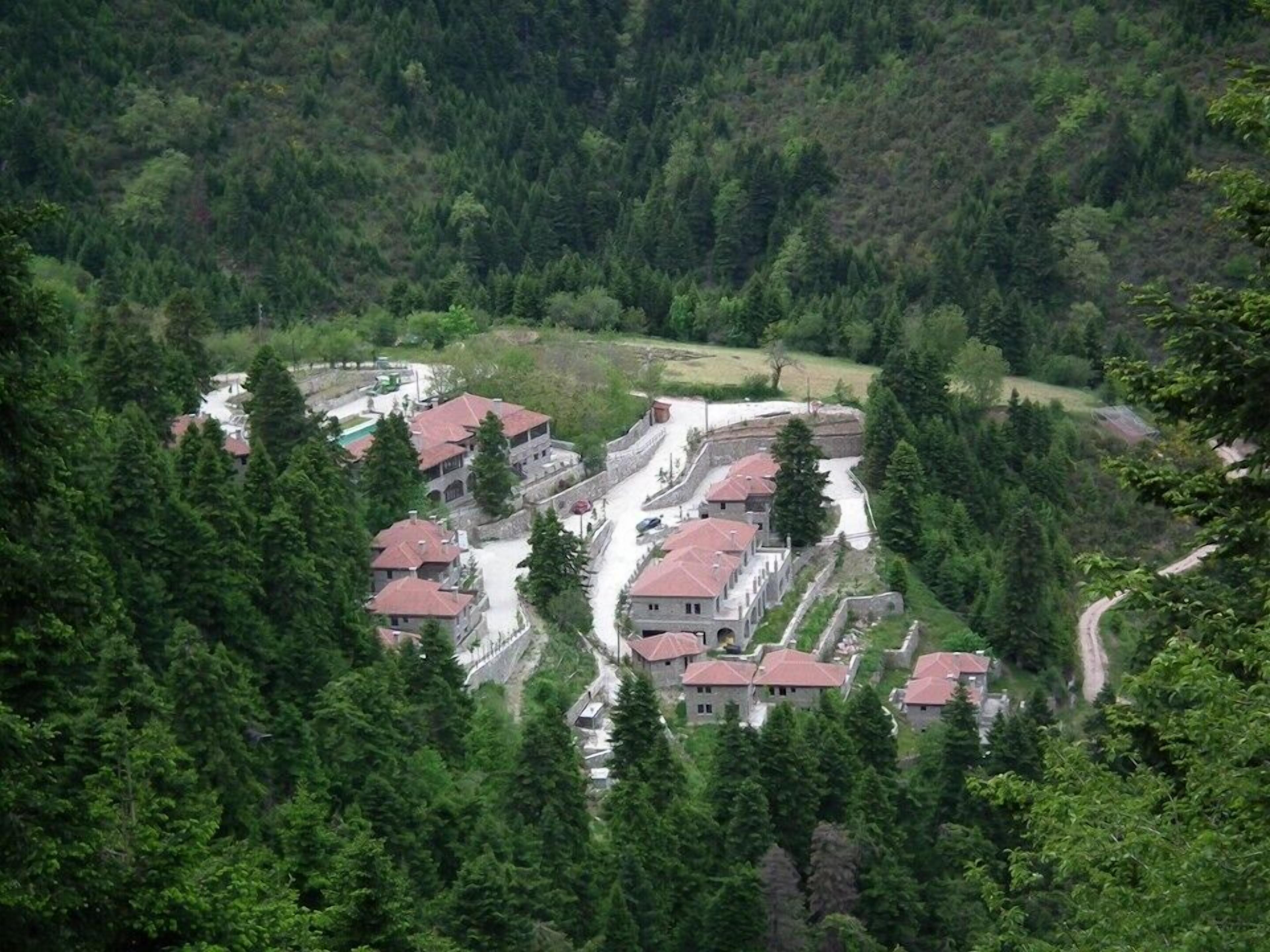 Eine gebirgige Gegend mit einer Ansammlung von Gebäuden mit roten Dächern, umgeben von dichtem Wald.