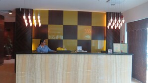 A reception desk with a checkered wall design, a receptionist, and hanging pendant lights. - The Mark's Lodge (Sandakan)
