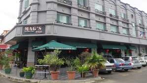 A multi-story hotel with a cafe named 'MAG'S CAFE' on the ground floor. There are several potted plants in front of the cafe. - The Mark's Lodge (Sandakan)