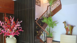 A staircase with a wooden handrail and black metal balusters, a potted plant, and a decorative horse statue. - The Mark's Lodge (Sandakan)