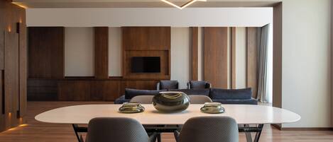A modern dining area with a round table, two chairs, a central decorative bowl, and a geometric pendant light.
