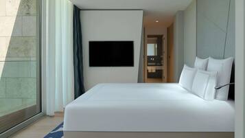 Een moderne hotelkamer met een groot bed, een flatscreen televisie aan de muur en een badkamer door een open deur zichtbaar.