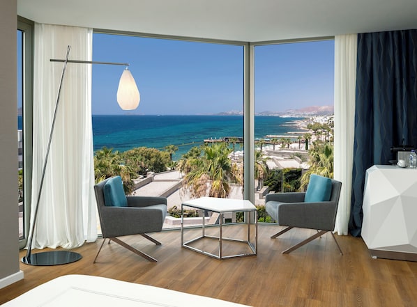 A modern room with a large window, two grey armchairs, a small table, and a floor lamp.