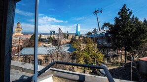 A view from a window overlooking a cityscape with a mix of historic and modern buildings, including a prominent tower and a glass skyscraper. - City Inn - Boutique Hotel Tbilisi (Tbilisi)