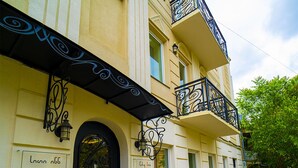 A building with a black wrought iron balcony, a black door, and a sign that reads "City Inn". - City Inn - Boutique Hotel Tbilisi (Tbilisi)