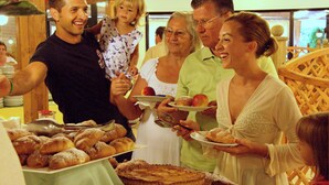 A group of people gathered around a table with various pastries and a pie, indicating a social event or gathering. - Villaggio Albatros (Lesina)