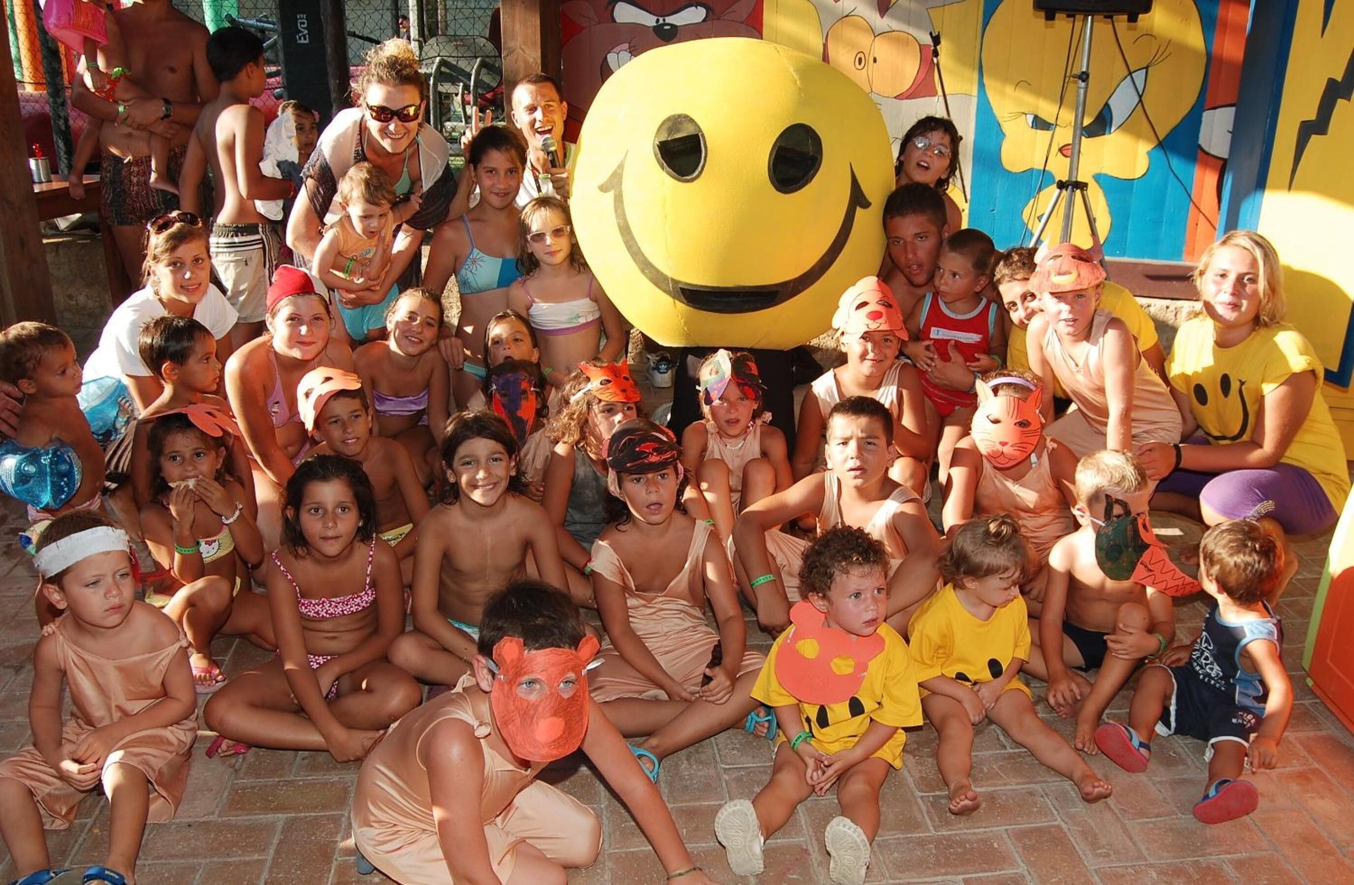 A group of people sitting on the ground, some wearing costumes and masks.