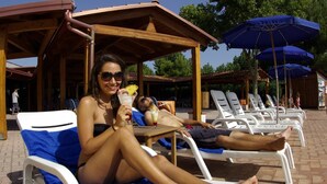 A poolside area with lounge chairs and umbrellas. - Villaggio Albatros (Lesina)