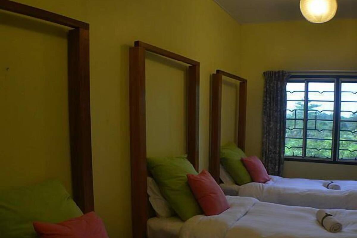 A hotel room with two beds, each with a pillow and a rolled towel.