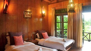 Una habitación acogedora con dos camas, paredes de madera y un amplio ventanal con cortinas.