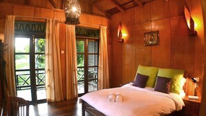 Un dormitorio con paneles de madera, una cama, cortinas y una lámpara colgante.