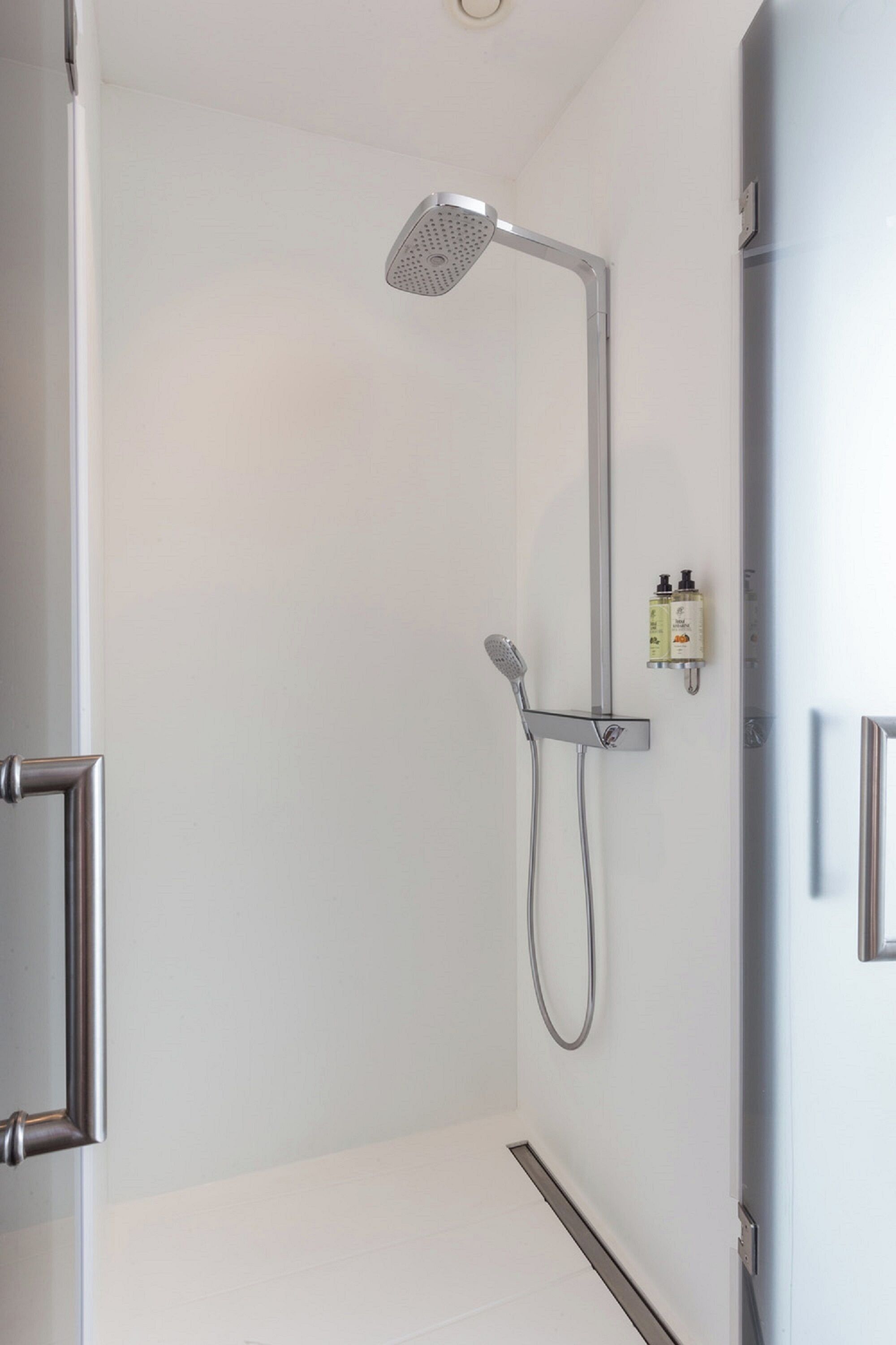 A modern shower with a handheld showerhead and a wall-mounted faucet.
