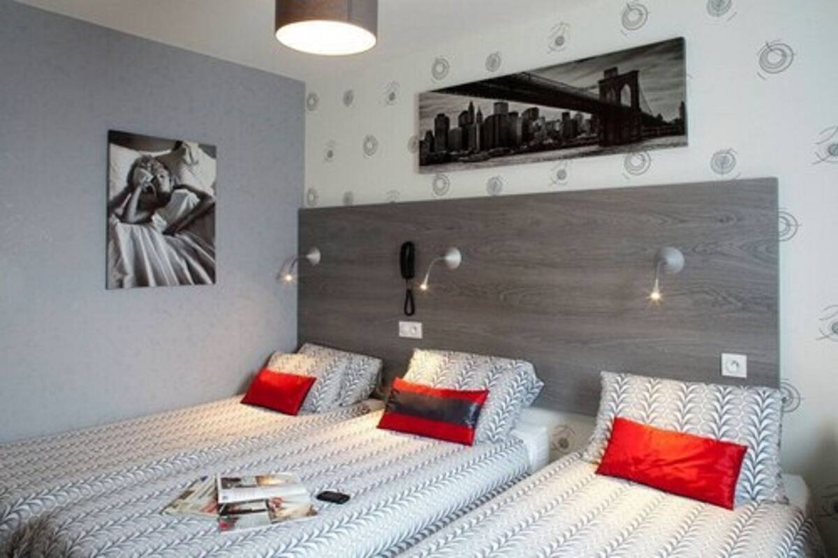 Quarto com duas camas, um quadro de paisagem urbana e uma cabeceira de madeira.