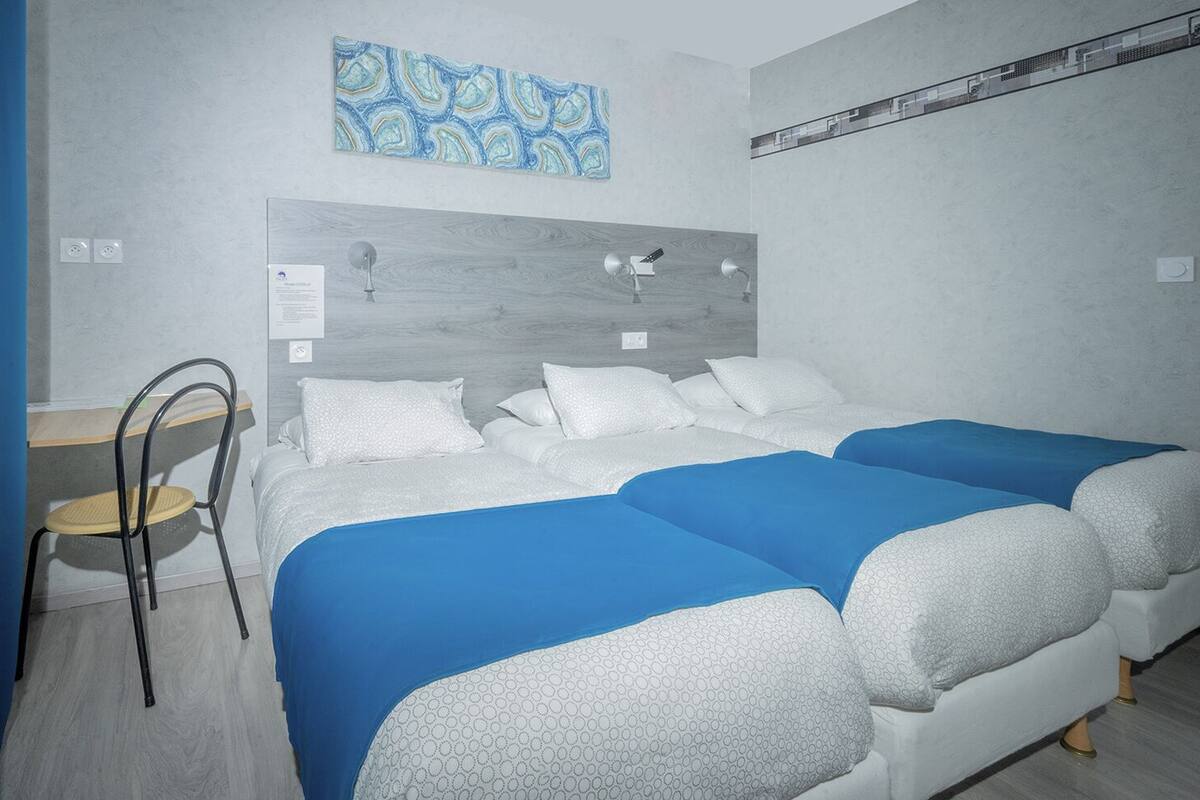 Quarto de hotel com uma cama, uma escrivaninha e uma cadeira.