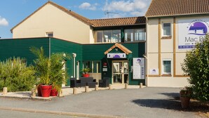 A hotel entrance with a green facade, a sign for 'MadBed' indicating room types, and a parking sign. - Hotel Mac Bed (Poitiers)