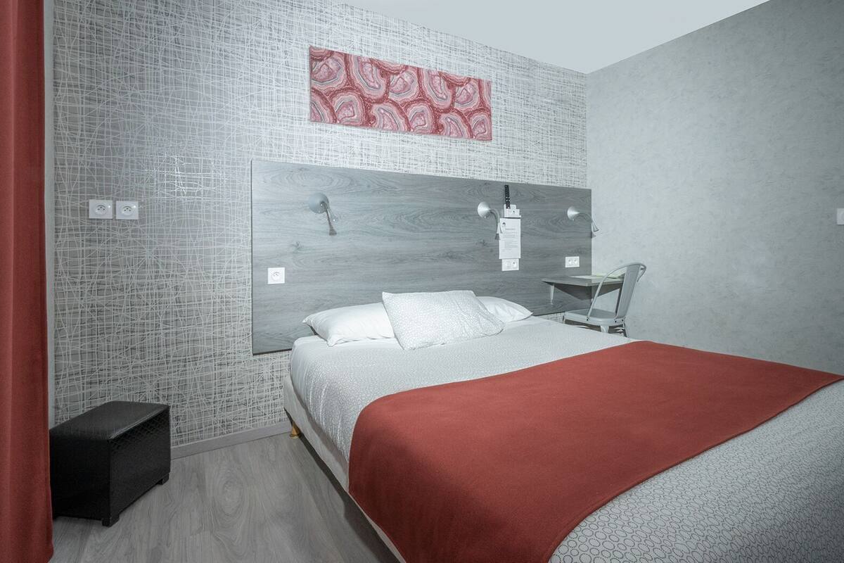Quarto com cama, mesa de cabeceira, cadeira e manta vermelha.