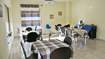 A dining area with checkered tablecloths, black chairs, and a blue tablecloth.
