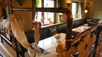 Ein Restaurantinneres mit Holzvertäfelung, Blick aus dem Fenster und ein Tisch mit einem Blumenstrauß.