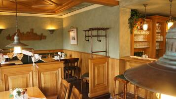 A cozy restaurant interior with wooden paneling, a bar area, and a seating arrangement.