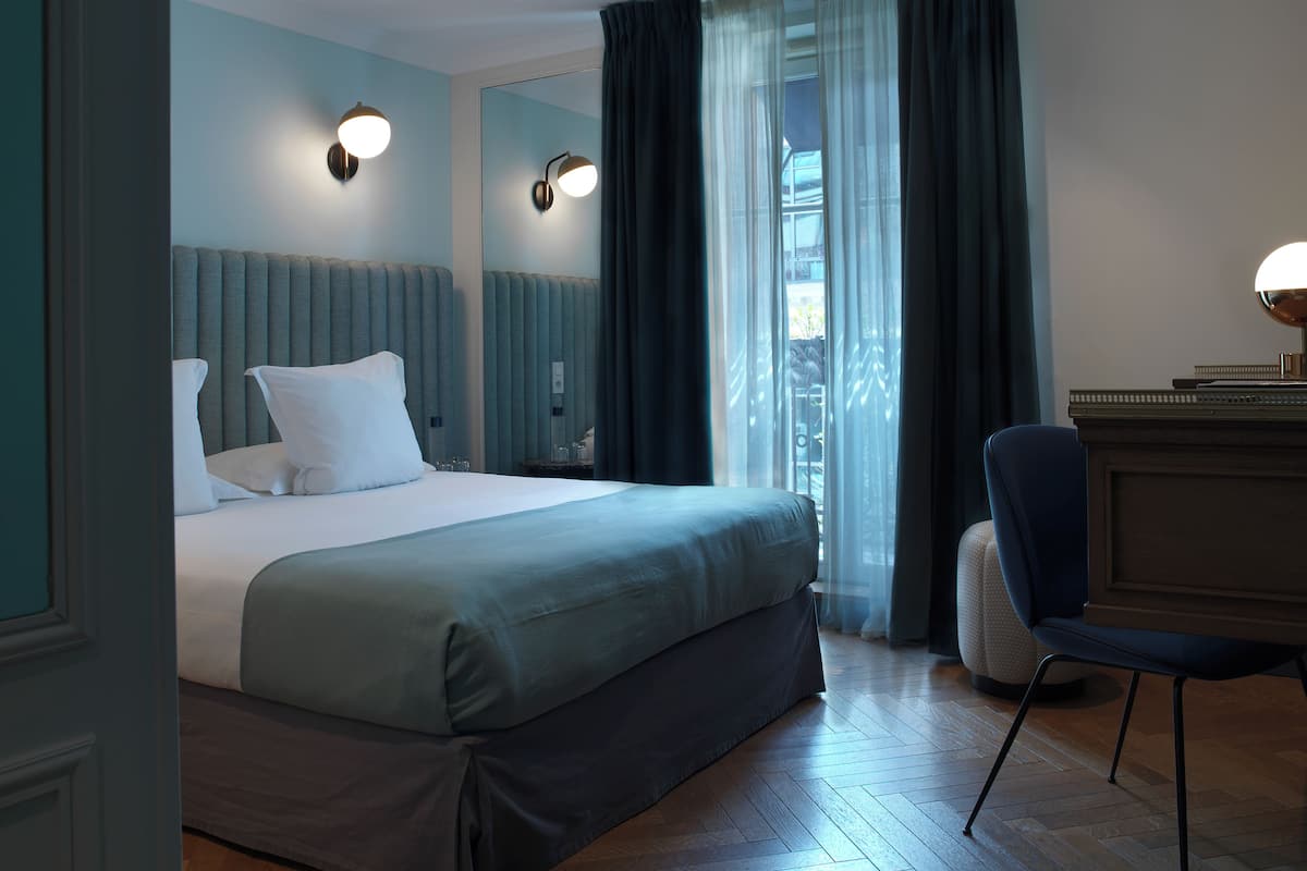 A modern hotel room with a large bed, a desk, and a chair.