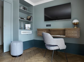 A modern room with a built-in TV, a desk, a chair, and a bookshelf.