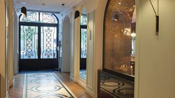 Un pasillo con piso estampado, arcos y luminarias colgantes.