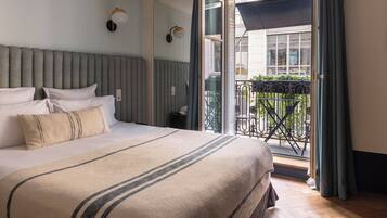 Habitación de hotel con una cama grande, vistas al balcón exterior y una ventana con cortinas.