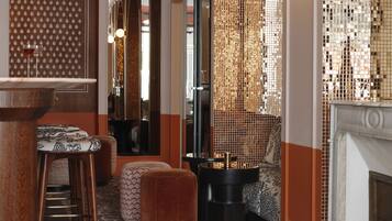 A bar area with stools, a patterned carpet, and a decorative wall with a mirror.