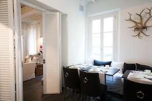 Un comedor con una mesa dispuesta para cuatro personas, un sofá y un adorno de cuernos en la pared.