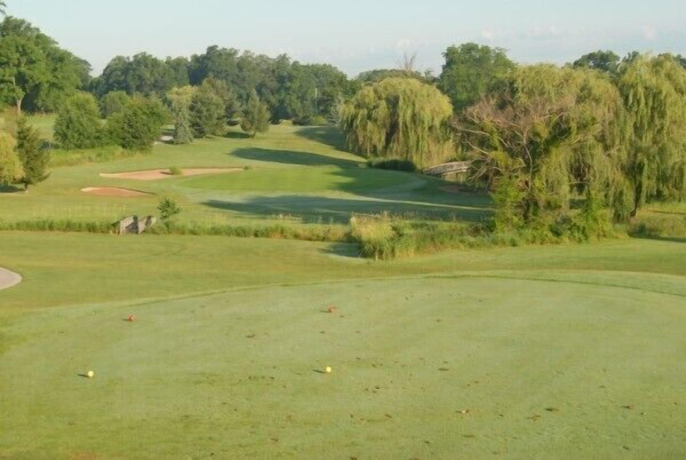 A golf course with a well-maintained green, sand bunkers, and trees in the background.
