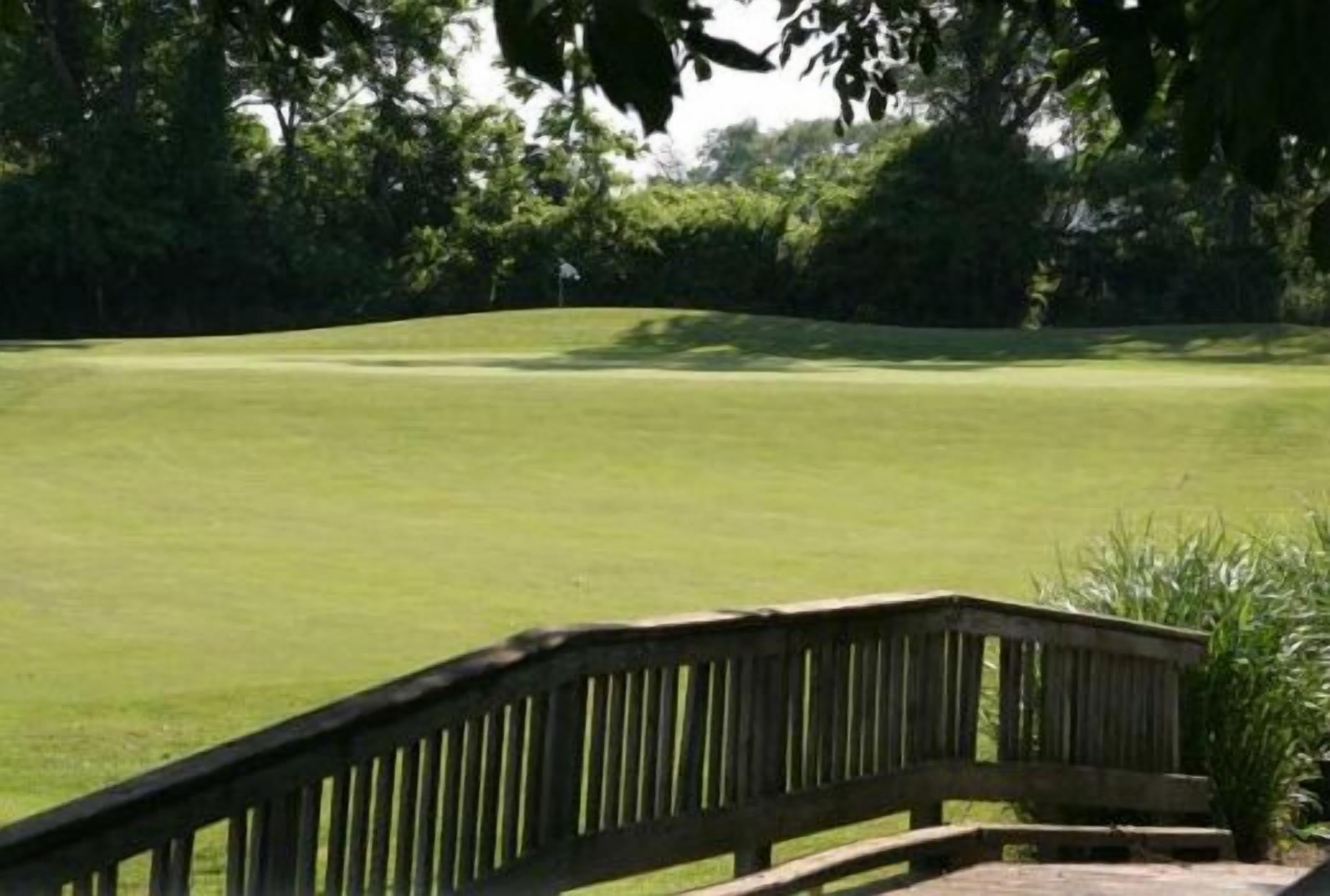 A golf course with a wooden bridge leading to the tee area.