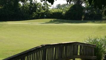 A golf course with a wooden bridge leading to the tee area.