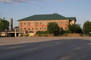 A large, rectangular building with a green roof and multiple windows. It has a flat facade and is surrounded by a paved area with trees and a fence. - Guest Quarters at The Bridges Golf Club (Abbottstown)