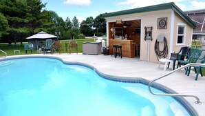 A swimming pool with a bar area, outdoor seating, and a covered patio. - Fairway Overnight & Extended Stay (Manchester)