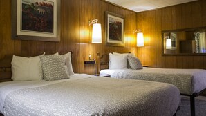 A hotel room with two beds, wooden paneling, framed artwork on the walls, and bedside lamps. - Fairway Overnight & Extended Stay (Manchester)