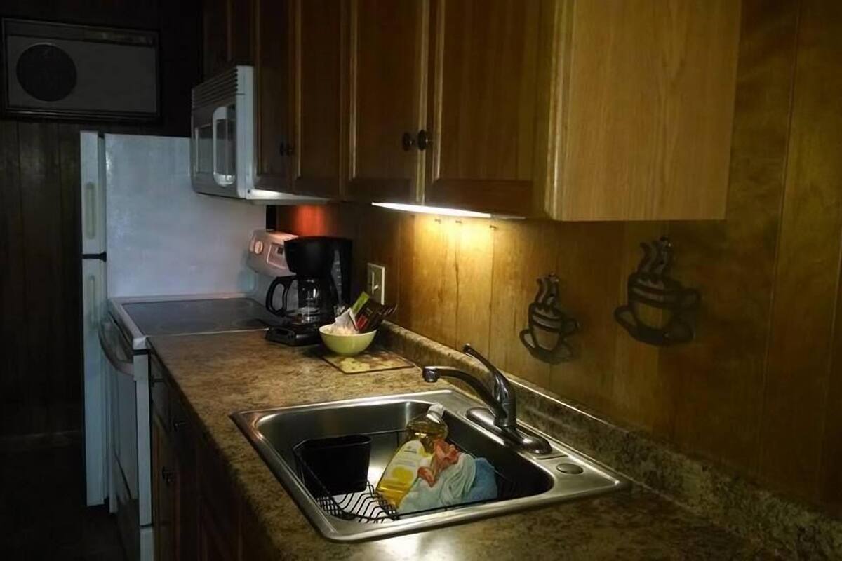 A kitchen with wooden cabinets, a microwave, a coffee maker, and a sink.