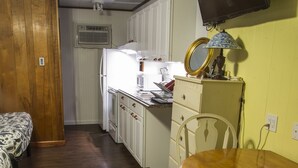 A compact kitchen with a refrigerator, microwave, and a small dining table with chairs. - Fairway Overnight & Extended Stay (Manchester)