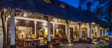 A hotel with thatched roofs, outdoor seating, and a pool area.