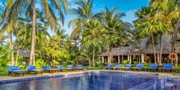 Una piscina techada, una piscina al aire libre, sombrillas