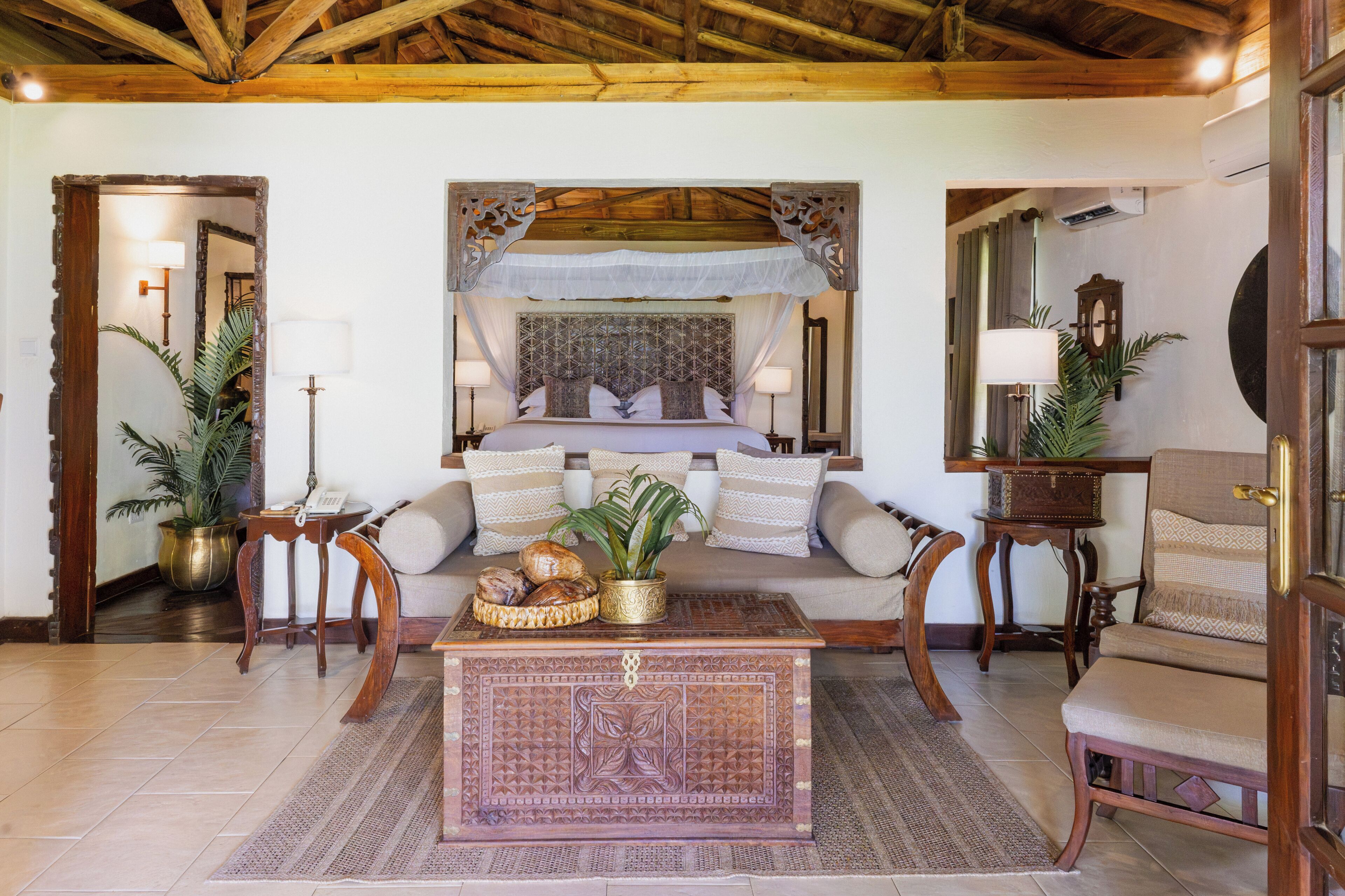 Una habitación con cama, sofá, mesa de centro y espejo.