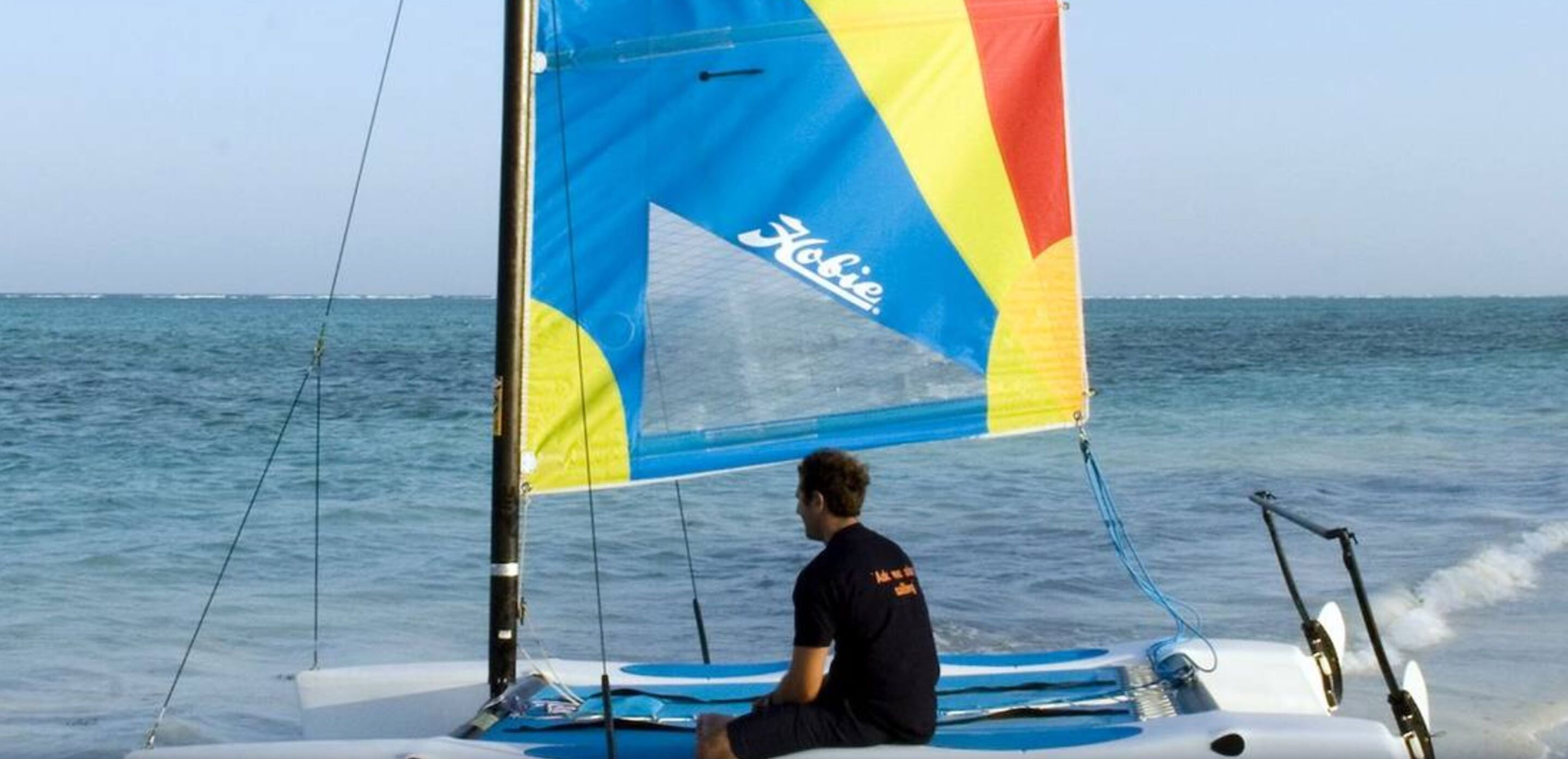 Una persona navegando en un velero con una vela colorida.