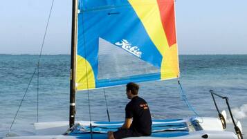 Una persona navegando en un velero con una vela colorida.