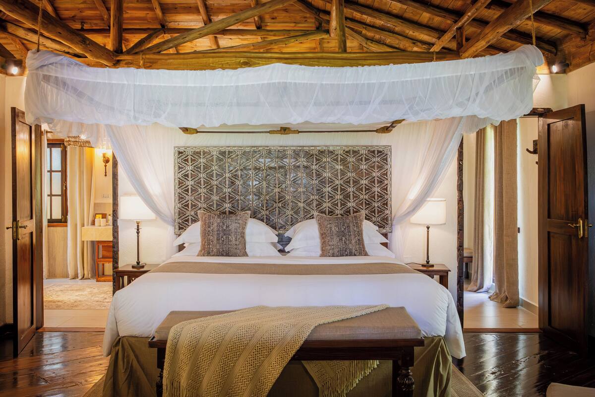 A room with a bed, a wooden ceiling, a patterned headboard, and a canopy.