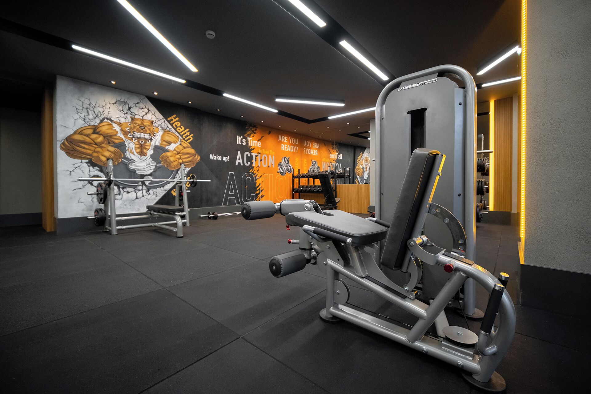 A gym with weight machines, a wall mural, and overhead lighting.