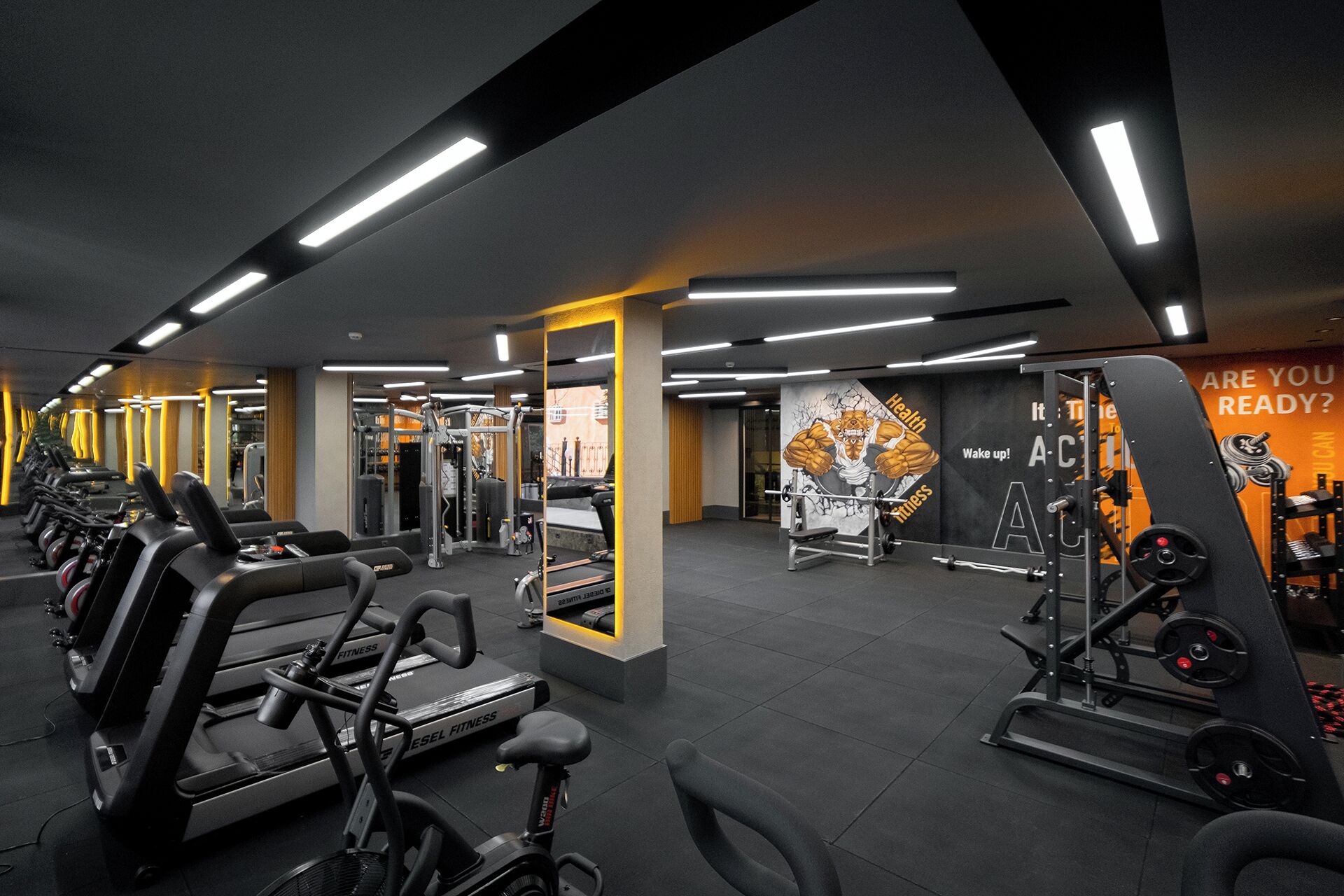 Een moderne sportschool met diverse fitnessapparaten, waaronder loopbanden, hometrainers en krachtapparaten.
