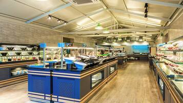 A modern restaurant interior with a central counter, multiple food display cases, and a brick wall backdrop.