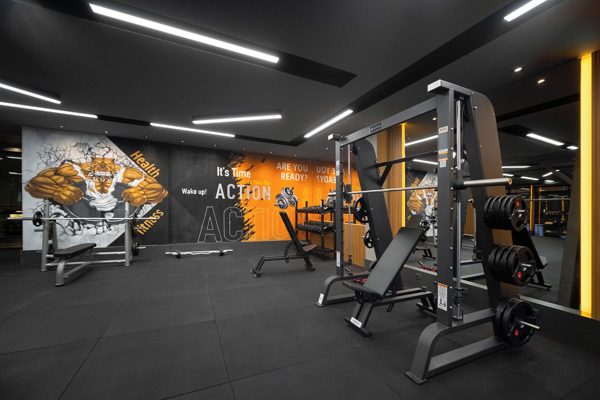Un gimnasio moderno con equipo de levantamiento de pesas, decoración inspiradora en las paredes y un interior limpio y bien iluminado.