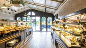 A buffet area with multiple food stations, a high ceiling with skylights, and a view of the outdoors through large windows. - Villa Sunflower Hotel (Alanya)